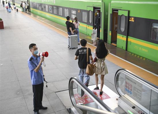 5月1日，重庆火车站工作人员在站台扶梯口引导旅客有序上车。? 新华社 图
